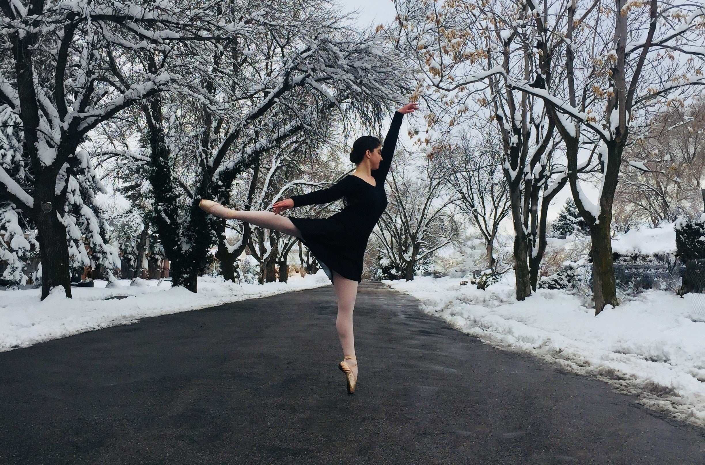 Woman wearing a black leotard and skirt on paved road in the snow