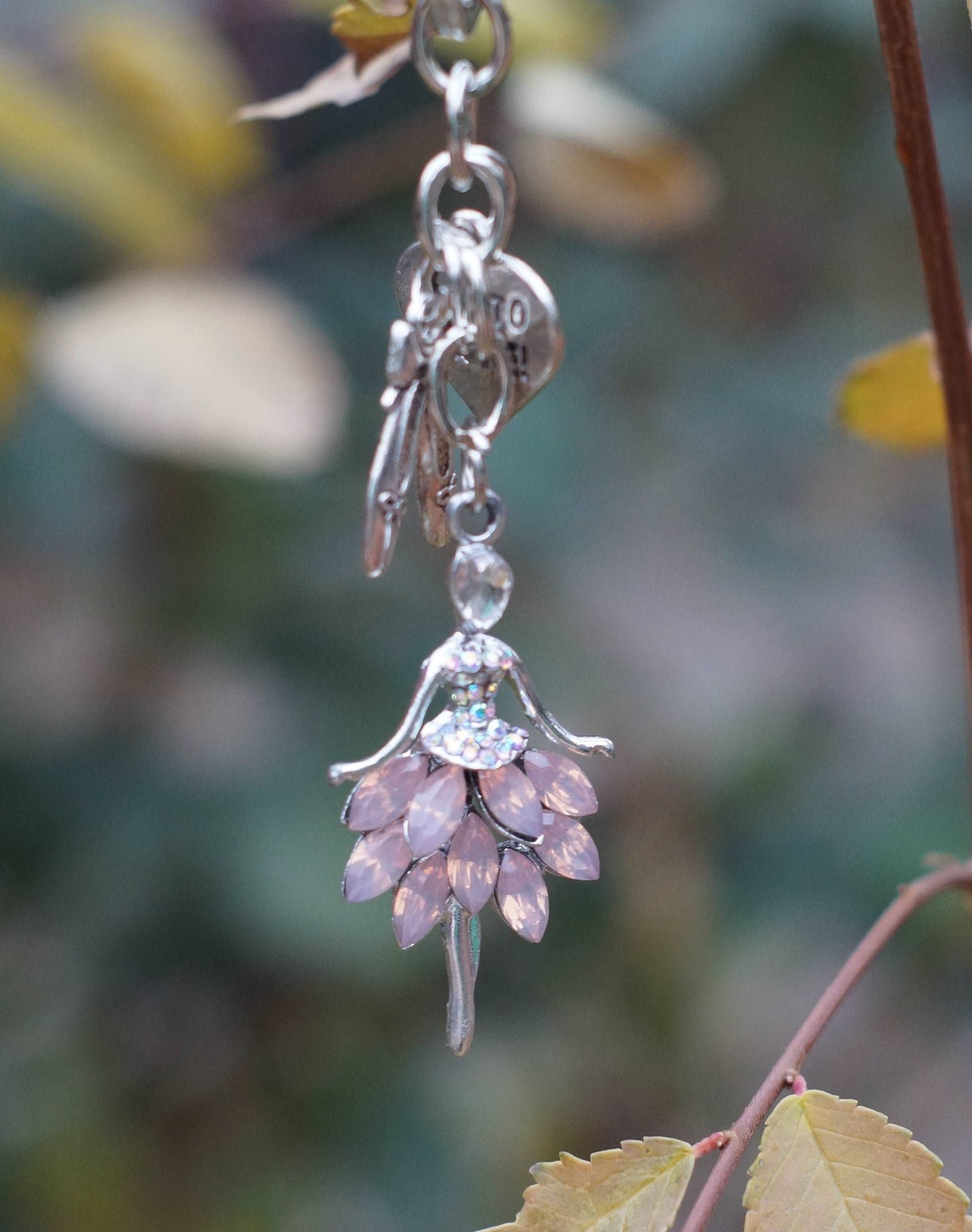 Pink crystal ballerina keychain hanging on rose bush