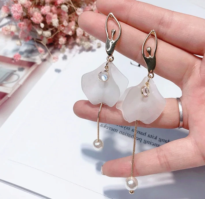 front of gold tone and white ballerina dangle earrings
