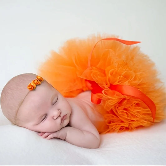 newborn wearing an orange tutu and headband