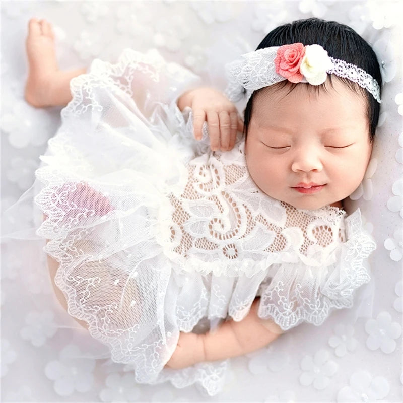 Neugeborenes trägt weißes Spitzen-Tutukleid mit passendem Stirnband