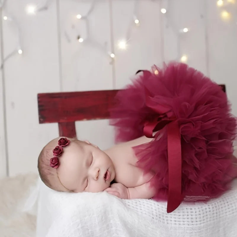 newborn wearing a burgundy tutu and headband