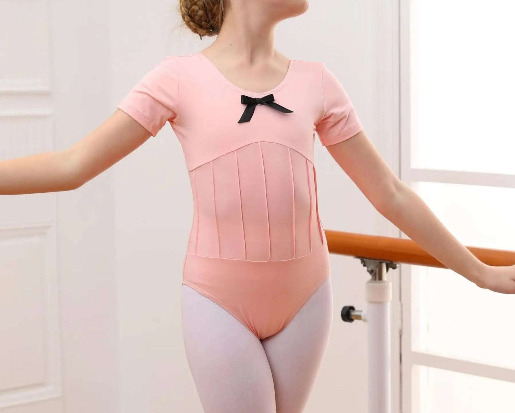 front of pink short sleeved girls leotard with black bow