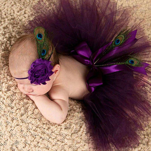 Bebê vestindo um tutu roxo com penas de pavão e bandana combinando