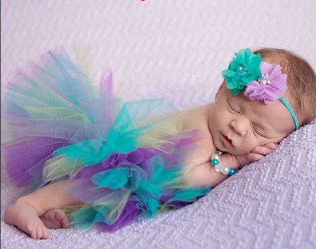 neugeborenes baby, das purpurrotes und blaues tutu trägt