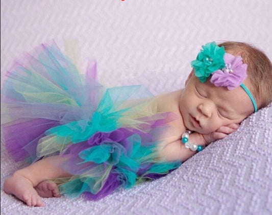 newborn baby wearing purple and blue tutu